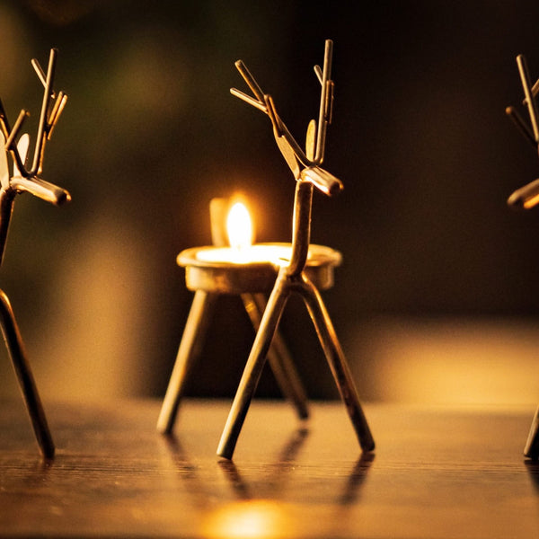 Six Christmas tea light holders arranged on a windowsill