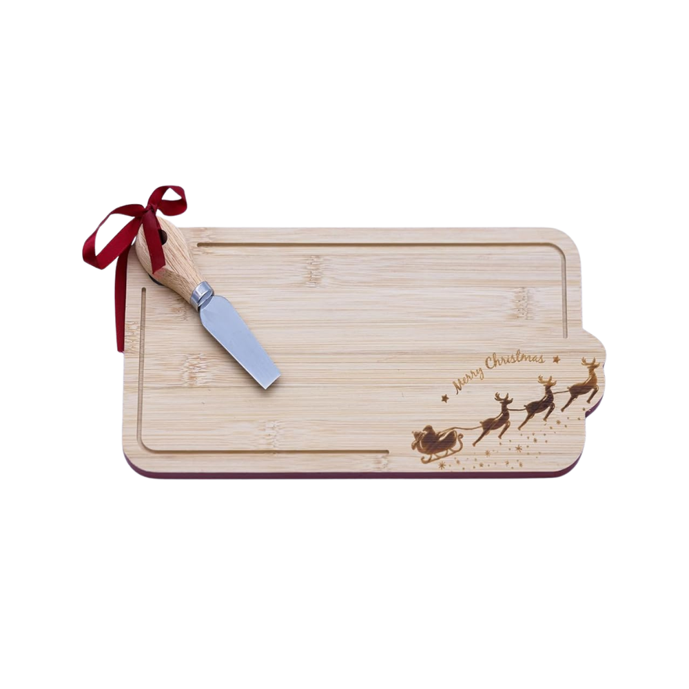 A rectangular bamboo holiday charcuterie board with a dark red border, engraved with 'Merry Christmas' and reindeer, styled on a table with cheese, crackers, grapes, and a cheese knife.