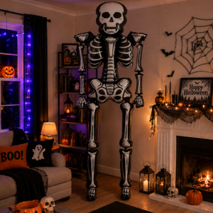 A large black and white skeleton floor decoration stands in a cozy, Halloween-decorated living room with a fireplace, pumpkins, and themed pillows.