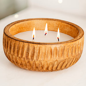 Candle in a wooden bowl with three flames on a light foreground