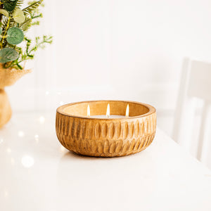 Woven basket candle with a plant on a white surface