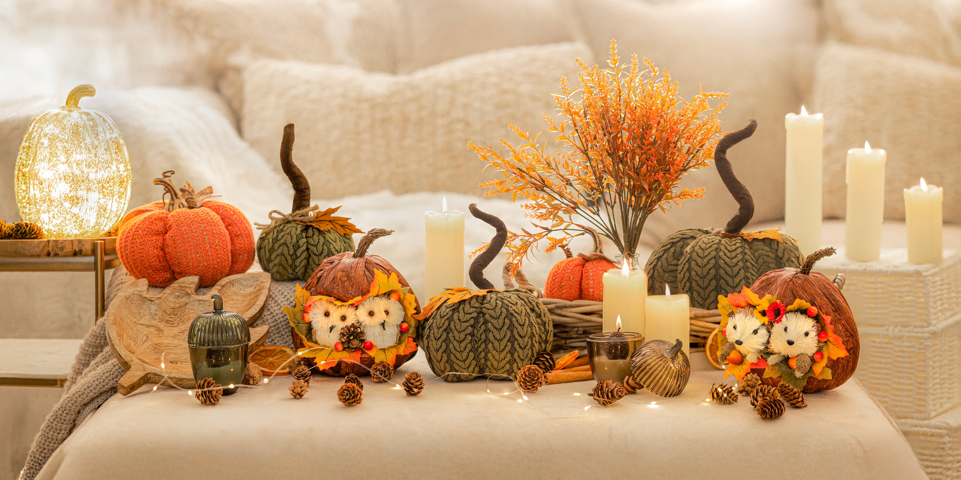 Decorative setup with pumpkins, candles, and autumn-themed decorations on a couch.