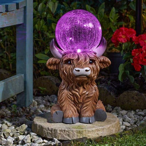 Highland cow solar ornament shown among flowers