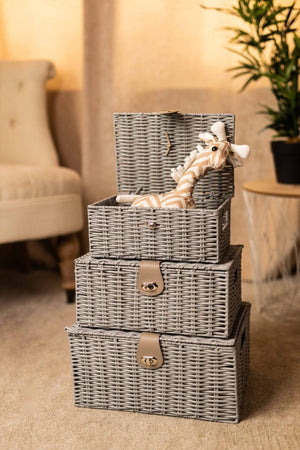 Set of three gray wicker storage baskets with handles in a living room setting.