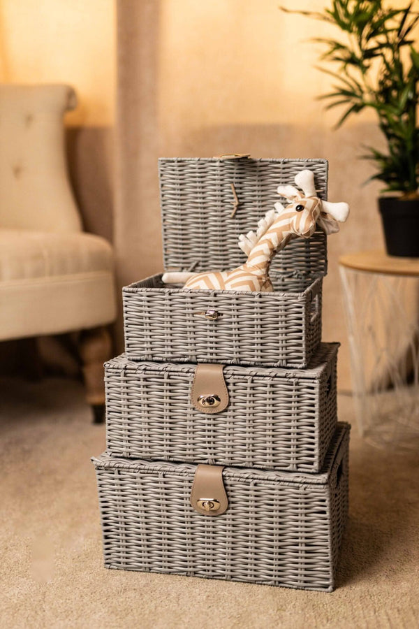 Set of three gray wicker storage baskets with handles in a living room setting.