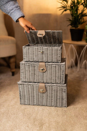 Stack of three woven storage baskets with a hand lifting the top one in a home setting.