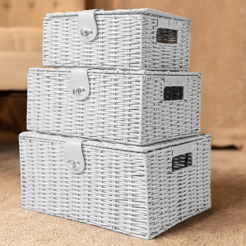 Set of three gray wicker storage baskets stacked on a wooden surface.