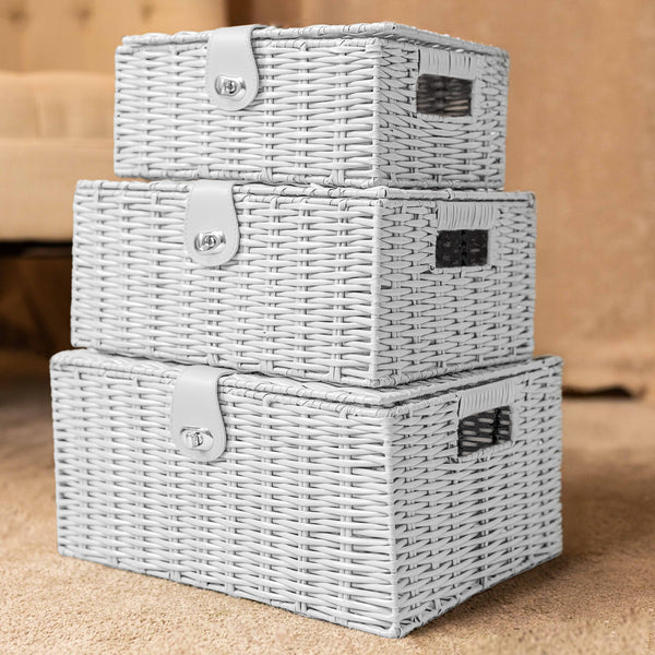 Set of three gray wicker storage baskets stacked on a wooden surface.