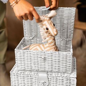 Person placing a zebra toy into a wicker basket with a blurred background