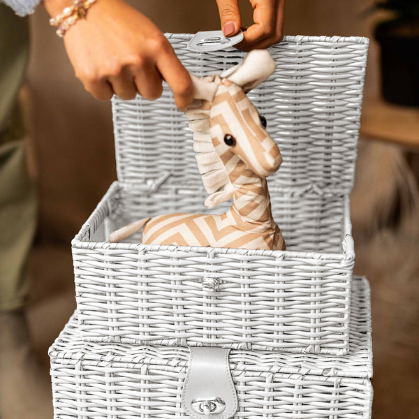 Person placing a zebra toy into a wicker basket with a blurred background