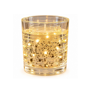 A lit glass candle holder with gold star-shaped glitter and glowing internal lights