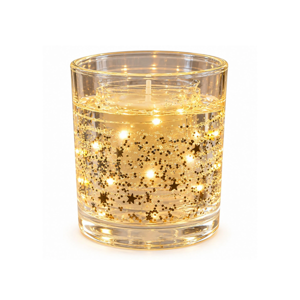 A lit glass candle holder with gold star-shaped glitter and glowing internal lights