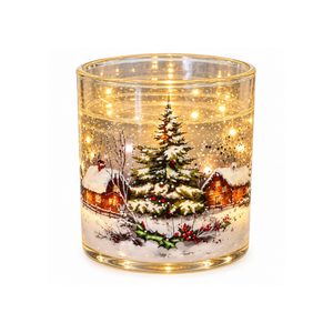A clear glass candle jar with a warm white LED light inside, featuring a printed winter village scene with a Christmas tree, cabins, snow, and falling leaves