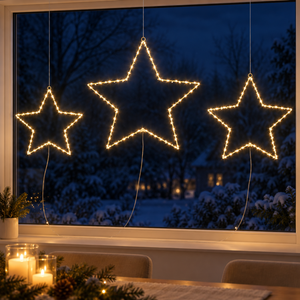 Set of three warm white LED Christmas stars hanging in a window overlooking a snowy garden.
