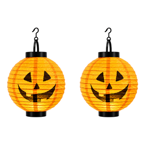 Two orange paper lanterns shaped like pumpkins with black jack-o'-lantern faces, each hanging from a black hook on a white background.
