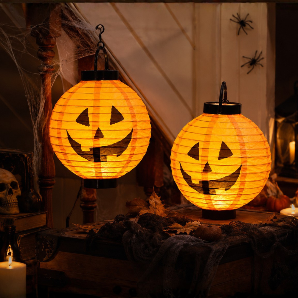 Two glowing orange jack-o'-lantern paper lanterns hanging in a Halloween-themed room with cobwebs, candles, and spider decorations.