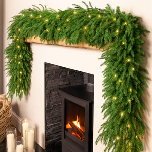 Decorative green garland with lights on a fireplace mantel.