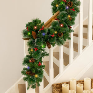 Decorative Christmas garland with lights and pinecones on a staircase.