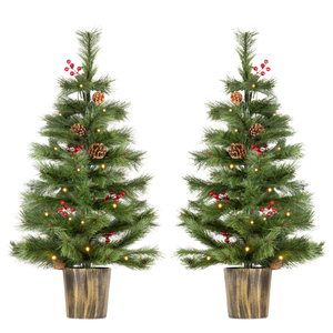 Two artificial Christmas trees with green needles, warm white string lights, pinecones, and red berries, each in a brown textured pot, shown on a plain white background.