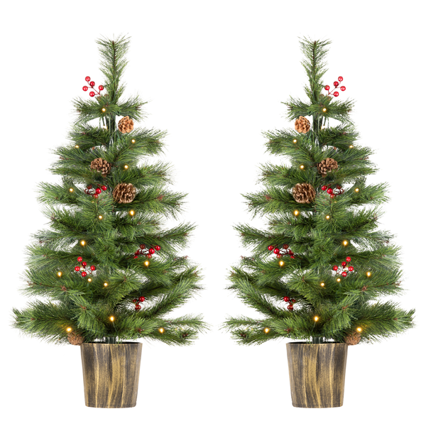 Two artificial Christmas trees with green needles, warm white string lights, pinecones, and red berries, each in a brown textured pot, shown on a plain white background.