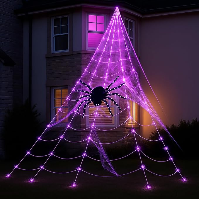 Halloween decorative spider web with a spider in front of a house at night.