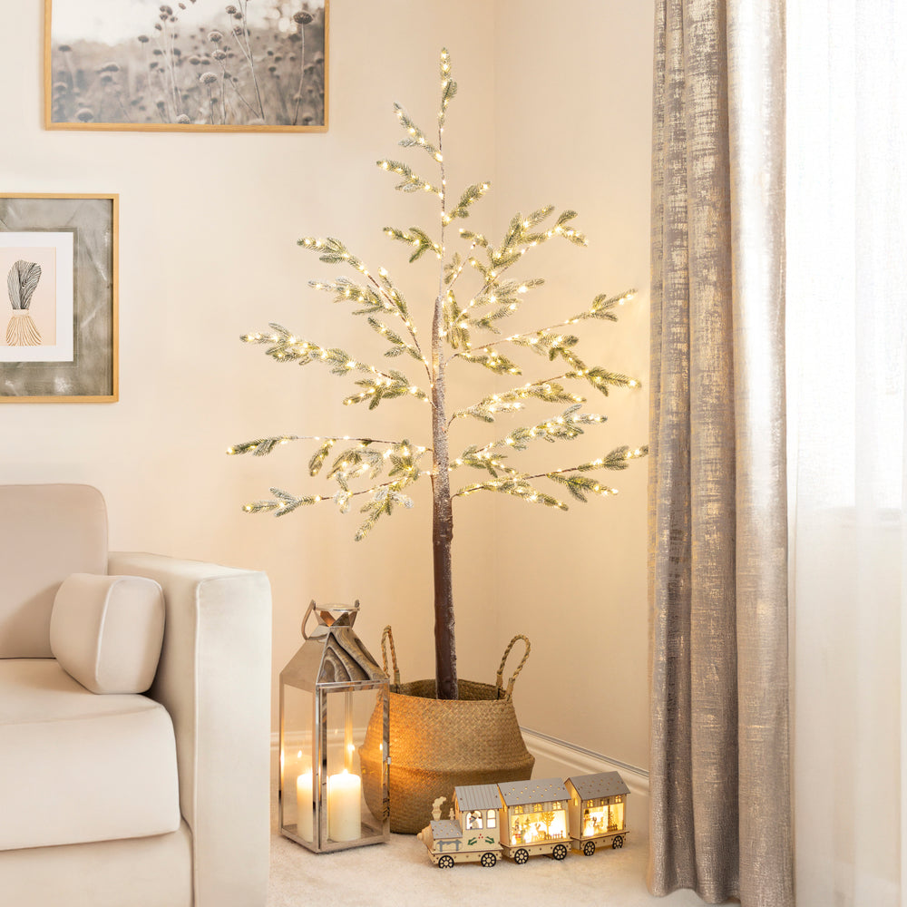 Decorative indoor tree with lights in a living room setting with Christmas decorations.