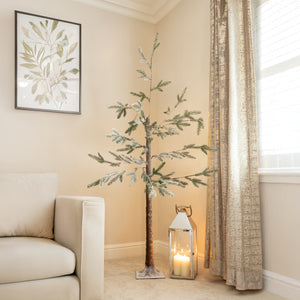 Decorative indoor tree with a lantern and candle in a room with beige walls and a window.