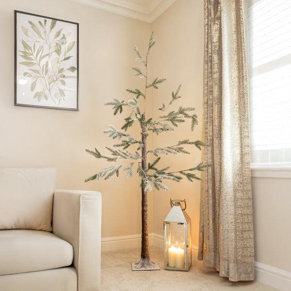 Decorative indoor tree with a lantern and candle in a room with beige walls and a window.