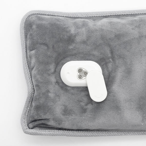 A gray plush heated pad with a white remote control on a plain white background.