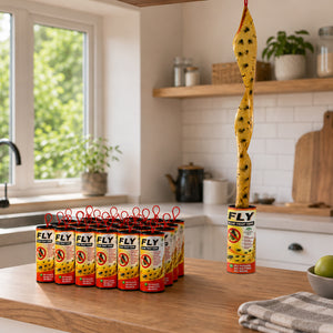 A kitchen countertop scene showing multiple tubes of FLY Fly Killer traps, with one trap hanging vertically above the counter. The traps are yellow with black spots and red hanging loops, set against a blurred modern kitchen background.
