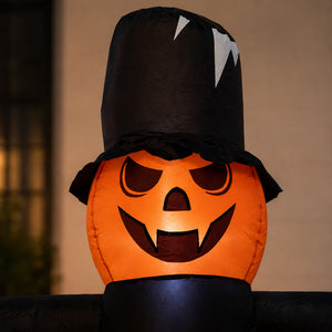 An inflatable Halloween decoration shaped like a jack-o'-lantern pumpkin wearing a tall black witch hat, photographed against a softly blurred indoor background.