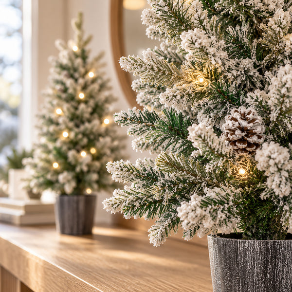 Close-up of snow flocked Christmas tree branches with pinecones and warm white LED lights.