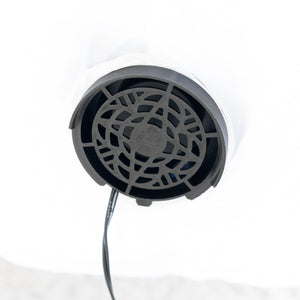 A close-up of a round black vent or grille component with a visible black cable extending downward, set against a bright white background.