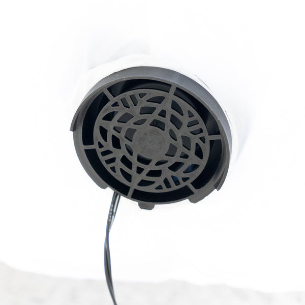 A close-up of a round black vent or grille component with a visible black cable extending downward, set against a bright white background.