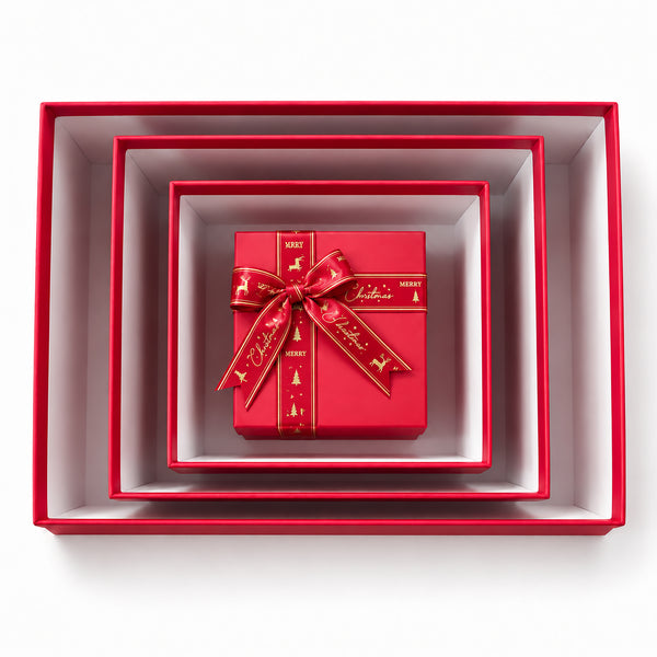 A small red gift box with a red ribbon bow and gold holiday print, nested inside a set of larger red gift boxes on a white background.