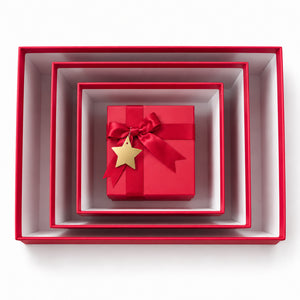 A set of nested square gift boxes in red and white, with a small red gift box tied with a red ribbon and a gold star ornament in the center, photographed from above on a white background.