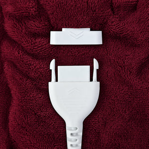 A close-up of a white plastic strap or buckle component placed on textured dark red fabric.