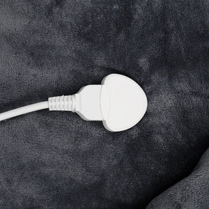 A close-up of a white electrical plug connected to a white cable, resting on a dark gray plush fabric surface.