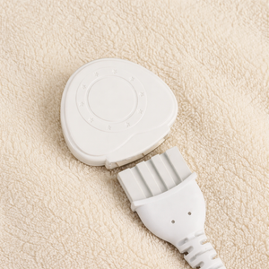 A close-up of a white electronic control module with a multi-pin connector plug, resting on a textured beige fleece surface.