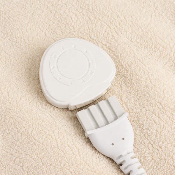 A close-up of a white electronic control module with a multi-pin connector plug, resting on a textured beige fleece surface.