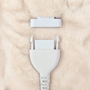 A close-up of a white plastic connector plug and matching white rectangular piece placed on a soft beige textured fabric background.