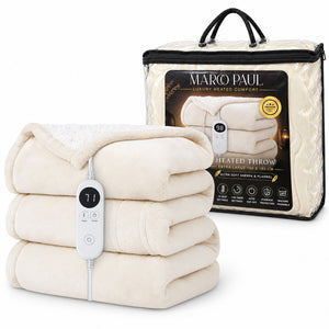 A stack of cream-colored heated throw blankets with a white digital controller in the foreground, shown next to its clear plastic packaging bag featuring the brand name 'MARCO PAUL'.