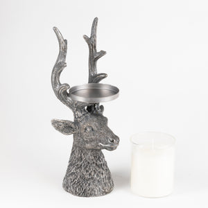 A gray deer head candle holder with antlers and a metal tea light tray on its head, shown next to a white tea light candle on a white background.