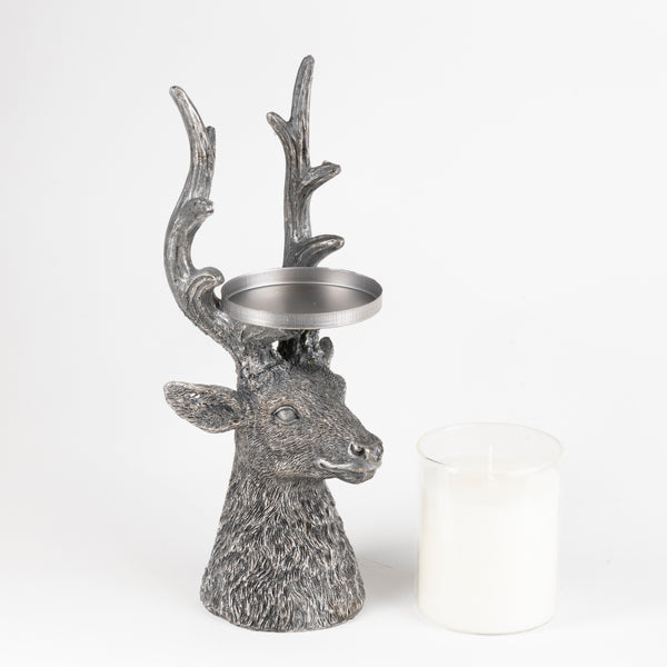 A gray deer head candle holder with antlers and a metal tea light tray on its head, shown next to a white tea light candle on a white background.