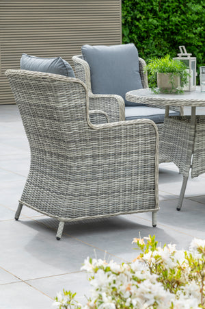 Outdoor patio furniture set with wicker chairs and a glass table on a patio.