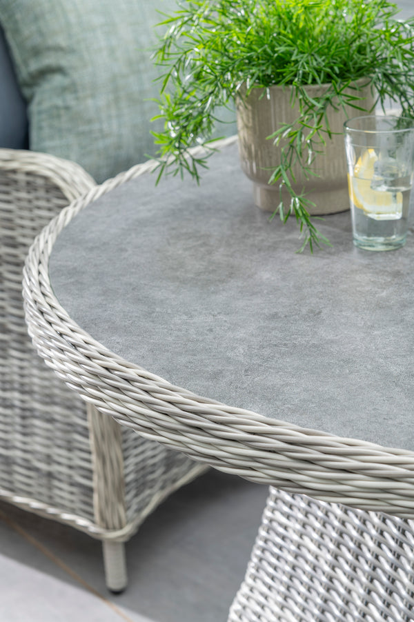 Wicker table with a glass of water and a lemon wedge on a patio setting.