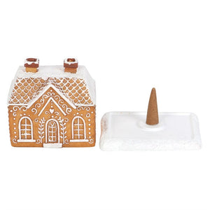 Decorative gingerbread house and incense cone on a white background