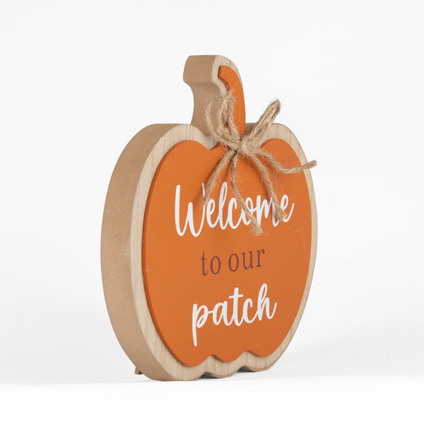 A decorative wooden pumpkin sign with a natural wood frame and stem, featuring an orange center panel that reads 'Welcome to our patch' in white and dark brown lettering, tied with a rustic jute bow, on a white background.