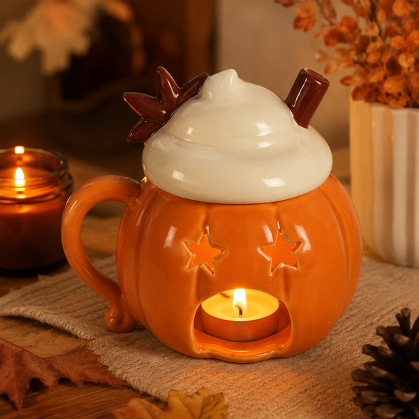 Orange pumpkin ceramic candle holder with star cutouts, whipped-cream lid and glowing tea light, styled with autumn décor.