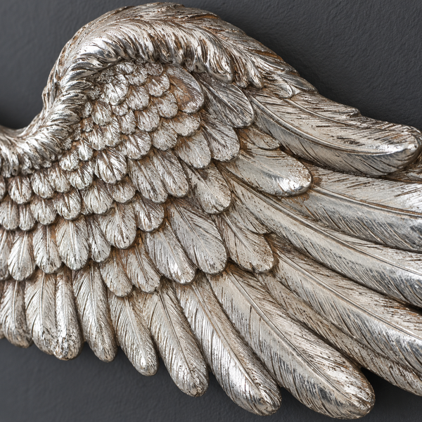 close up shot of a decorative silver angel wing showing the feather texture and distressed silver finish